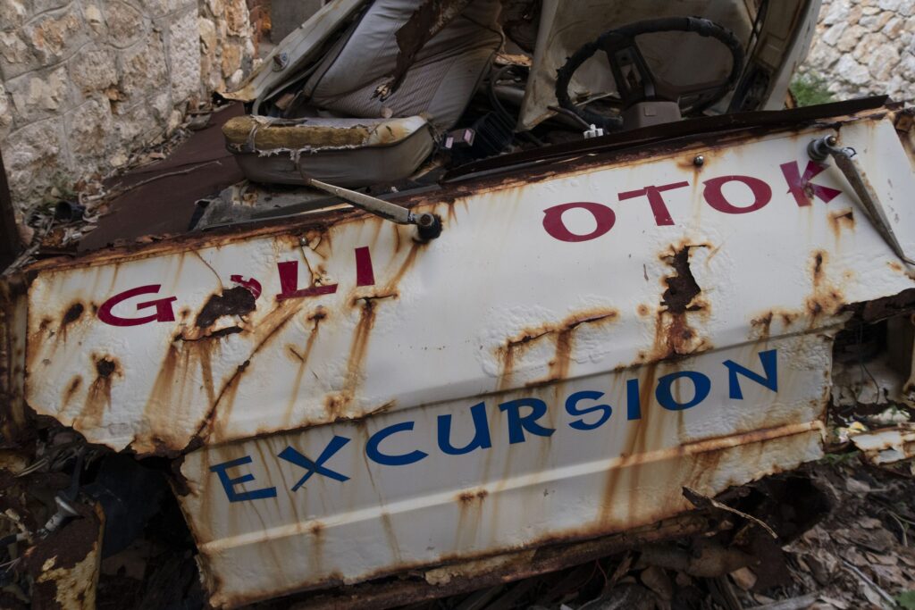 Verrostete Touristenbahn mit der Aufschrift „Goli otok Excursion“ zwischen Ruinen
