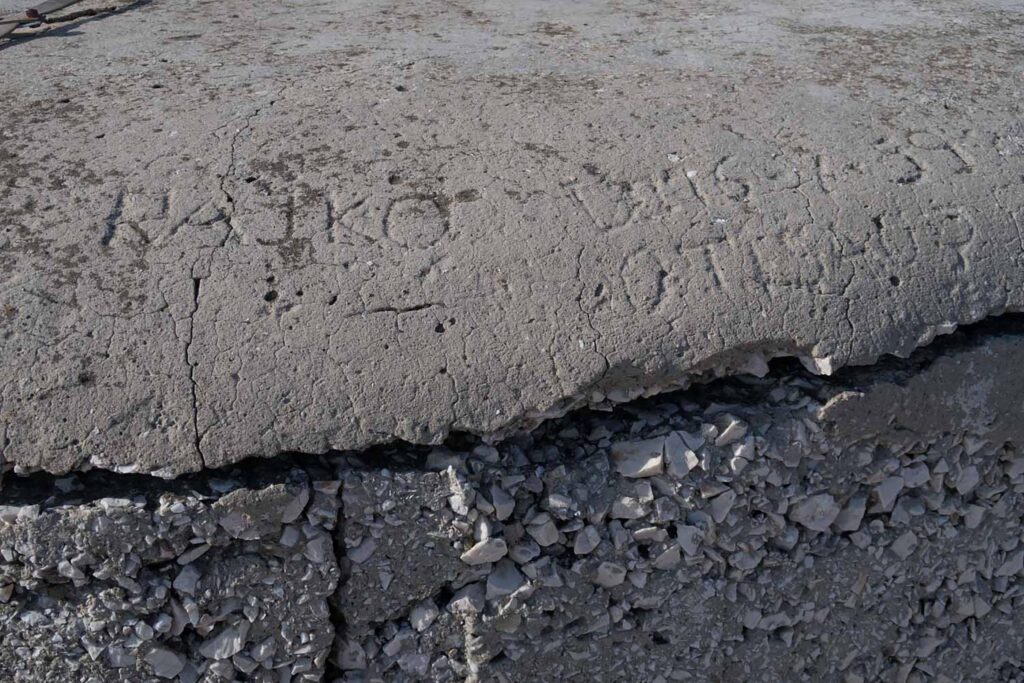In eine Betonplatte geritzte Inschrift