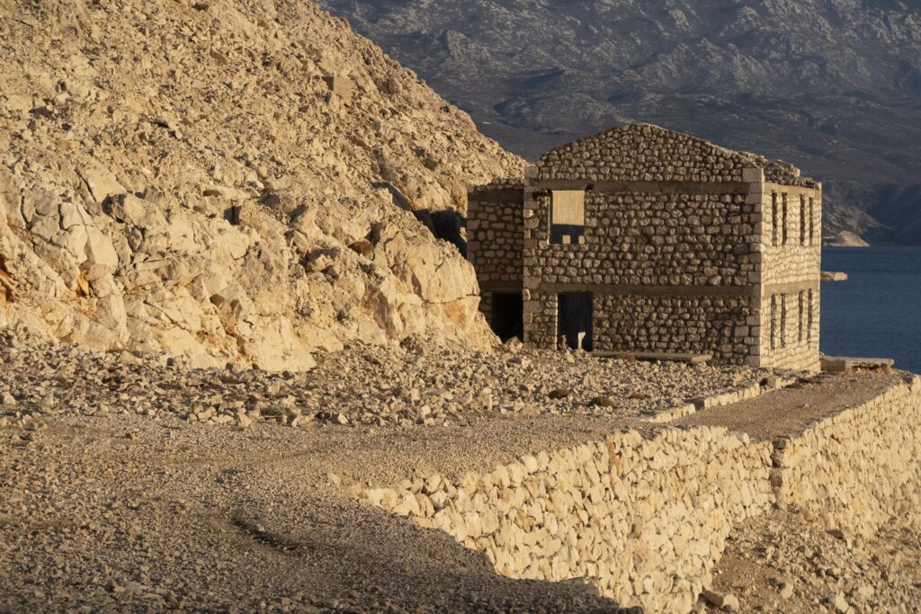 Zweigeschossiges Steingebäude in einer felsigen Landschaft