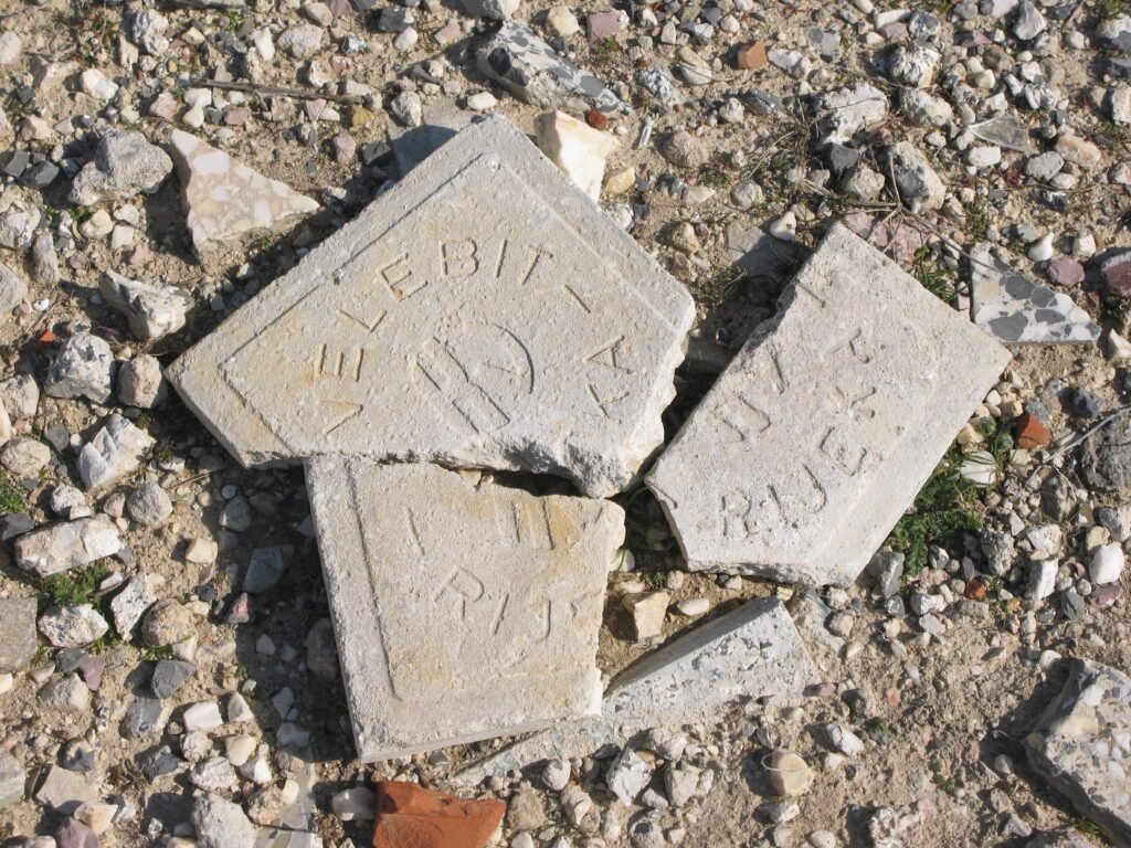 Zerbrochene Steinfliesen mit eingeprägter Aufschrift zwischen Steinen