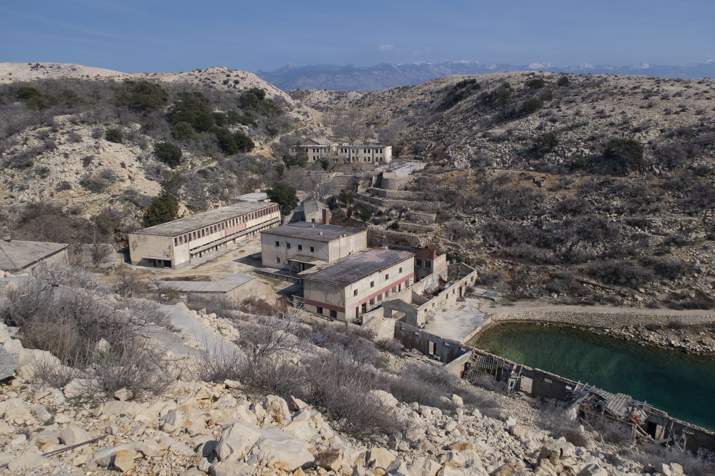 Blick von oben auf einen Gebäudekomplex an einer Bucht auf Goli otok
